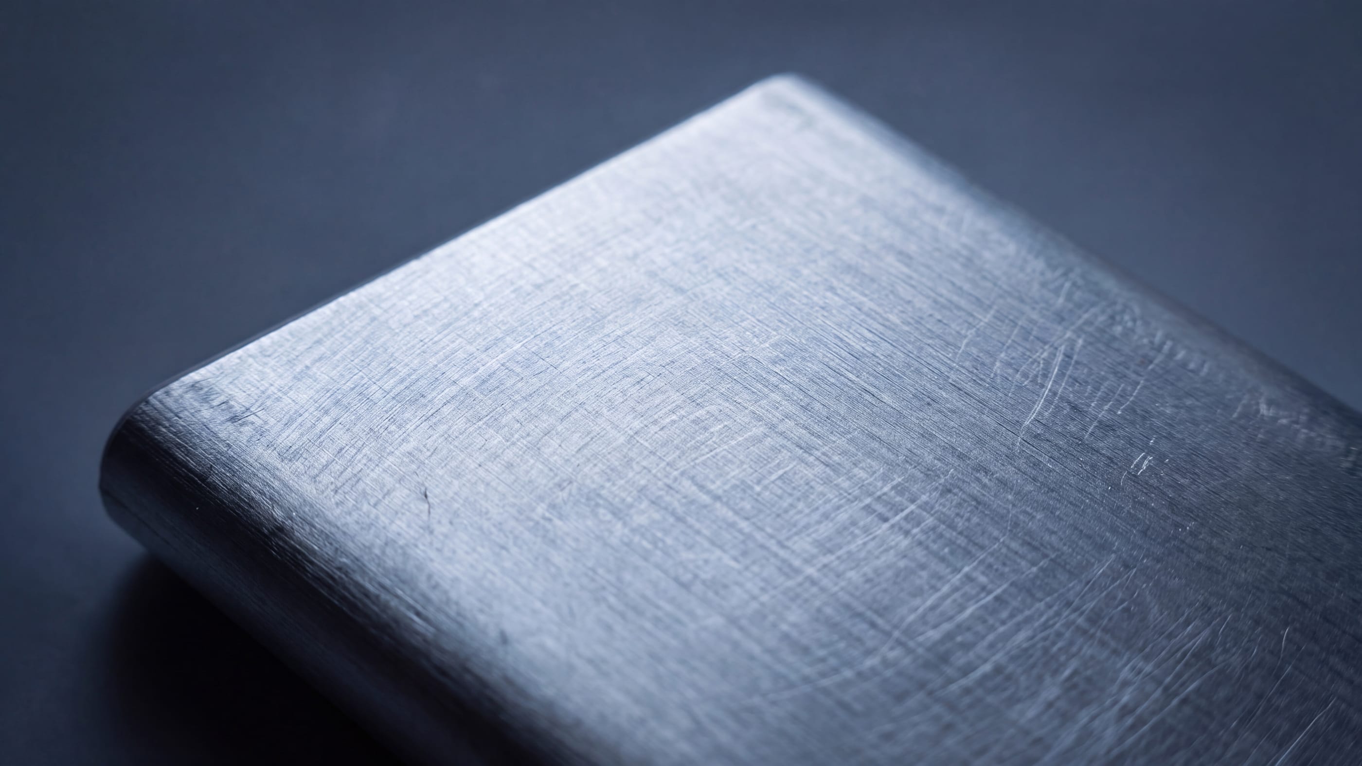 Makroaufnahme der gebürsteten Aluminiumoberfläche einer unbedruckten Powerbank im Streiflicht, die feine Schleifstruktur des Metalls ist deutlich sichtbar.