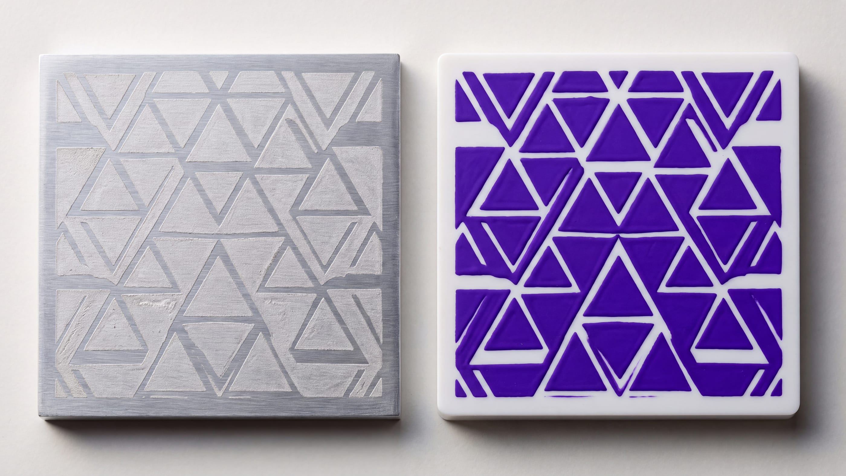 Zwei quadratische Musterplatten nebeneinander: links ein Dreiecksmuster matt in eine Aluminiumplatte graviert, rechts dasselbe Muster als violett aufgetragene Farbschicht auf weißem Kunststoff